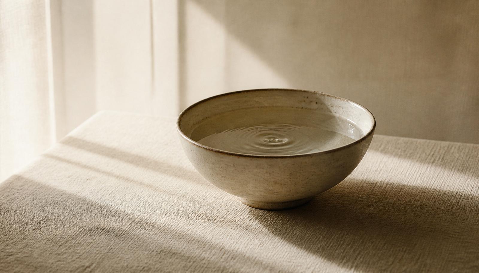 Still water in a ceramic bowl in soft window light